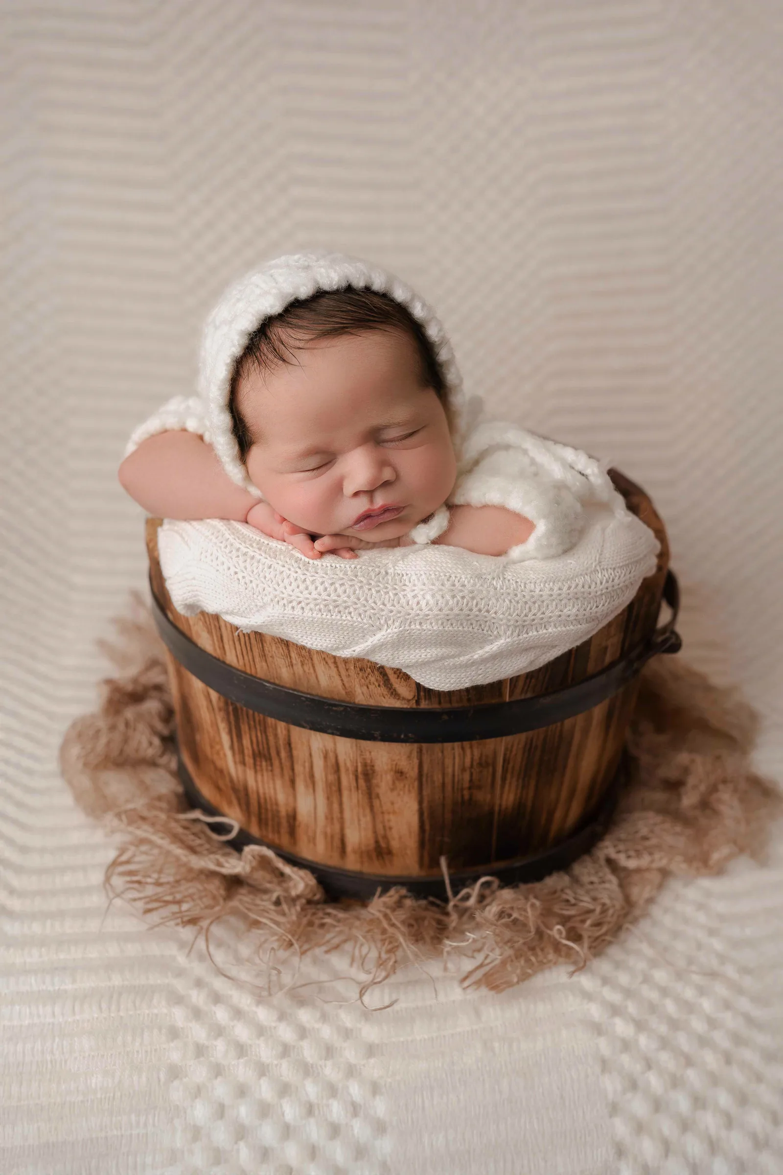 Recién nacido dormido en cubeta de madera — sesión newborn en Ciudad Juárez